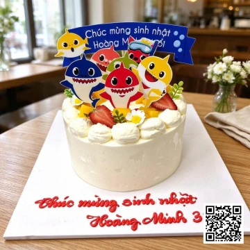Bánh sinh nhật tròn Baby Shark phủ kem tươi màu trắng ngà, trang trí topper gia đình cá mập rực rỡ và trái cây tươi.