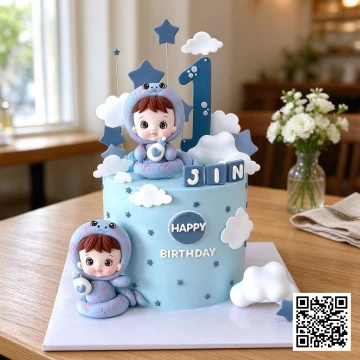 Bánh sinh nhật bé trai 1 tuổi hình em bé mặc đồ rắn chibi, màu xanh pastel, trang trí mây sao và số 1.