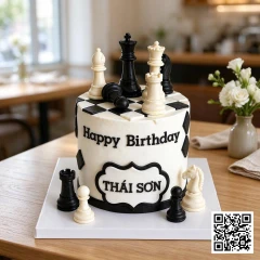 Bánh sinh nhật hình tròn chủ đề cờ vua với bàn cờ đen trắng và quân cờ 3D.