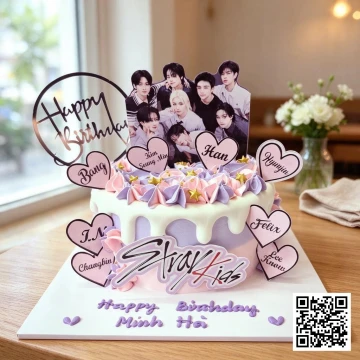 Bánh sinh nhật Stray Kids màu hồng pastel với hình ảnh 8 thành viên và logo nhóm, trang trí kem chảy và hoa kem.