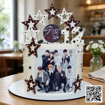Bánh sinh nhật hình tròn màu trắng ngà trang trí hình ảnh nhóm nhạc K-pop Stray Kids với topper ngôi sao và kem chảy.